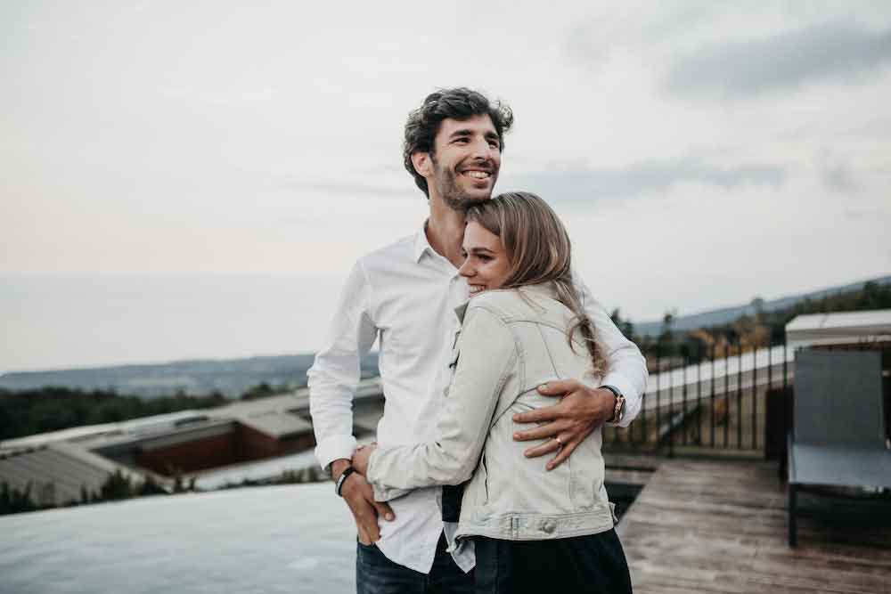 Women gives man a big hug outside the view of their house.