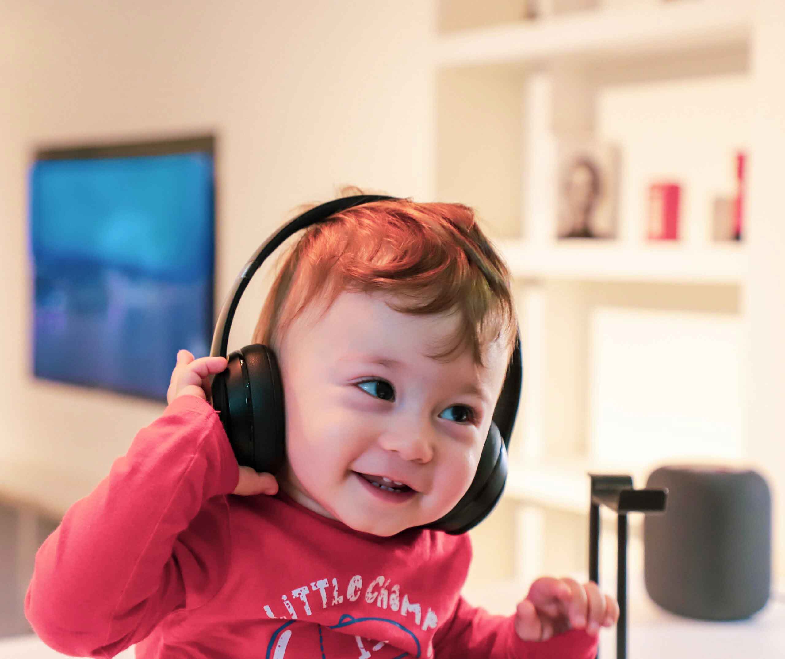 Little kid laughs with earphones on.